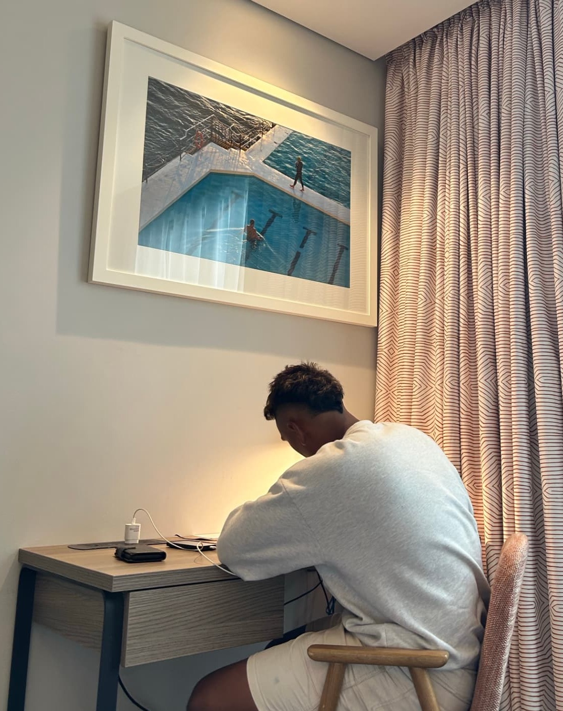 Teokotai working at a desk in the Khaiana studio beside framed artwork